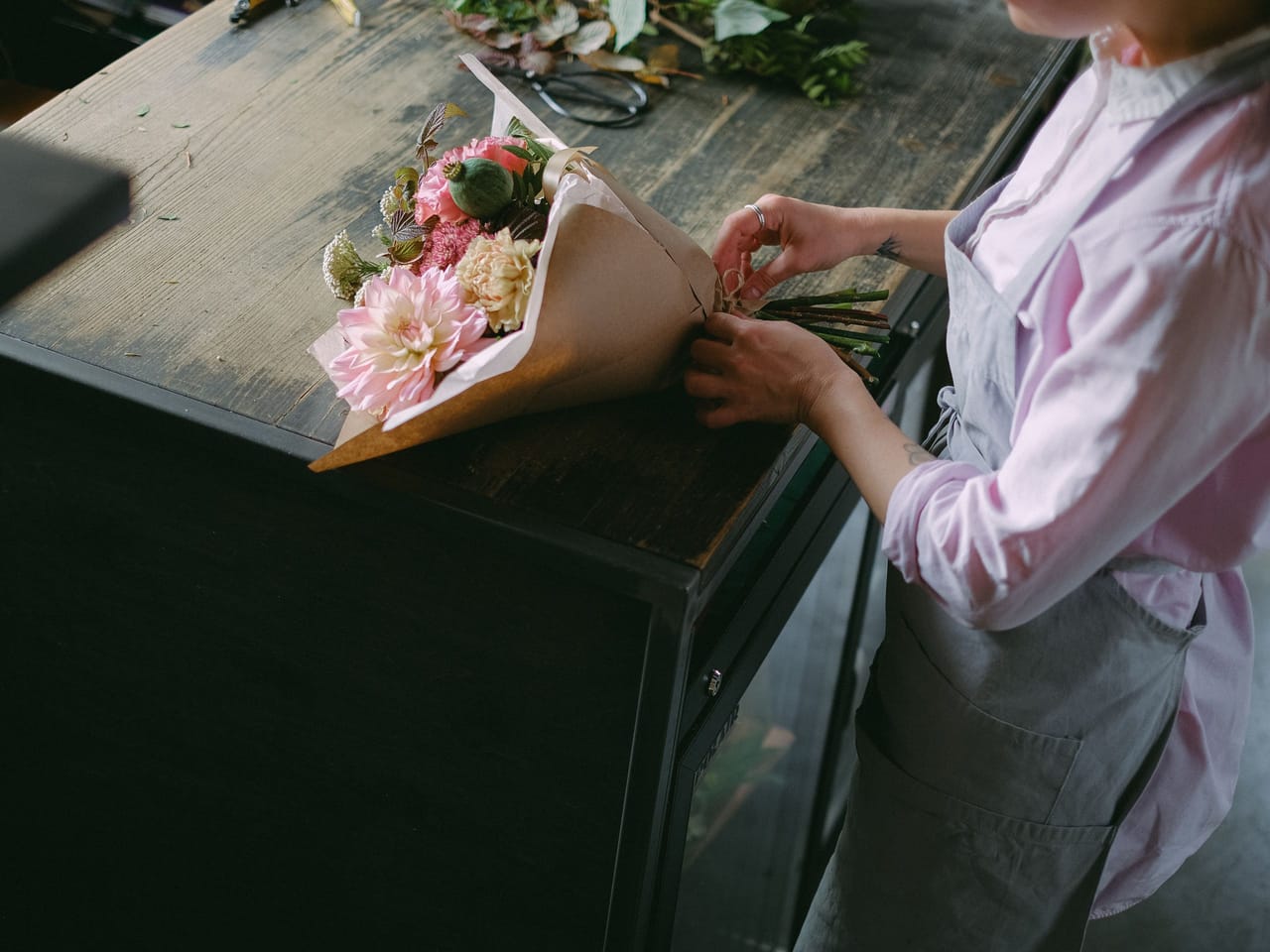 Fleuriste emballant un bouquet au comptoir de la boutique