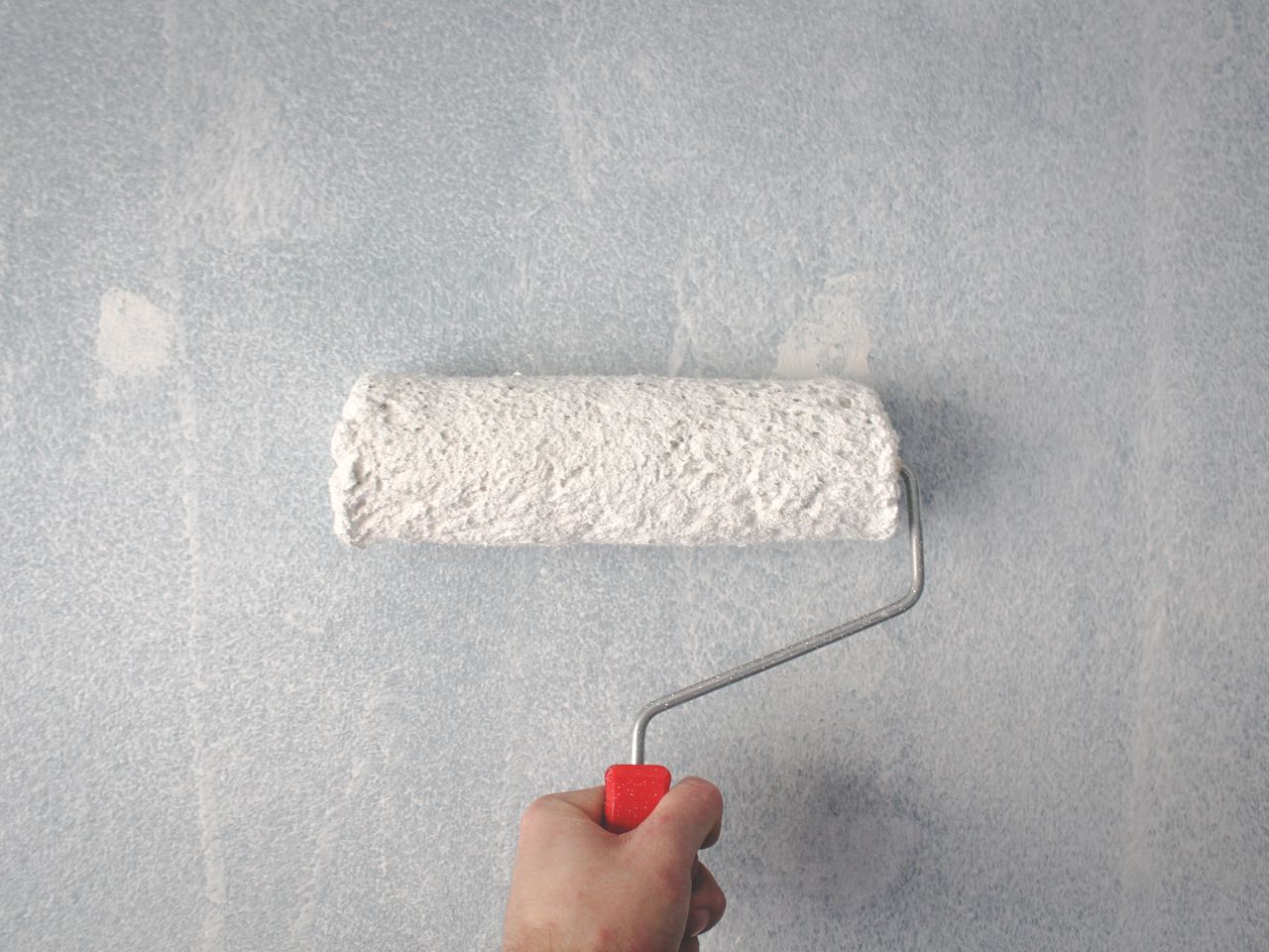 Peintre appliquant de la peinture claire au rouleau sur un mur