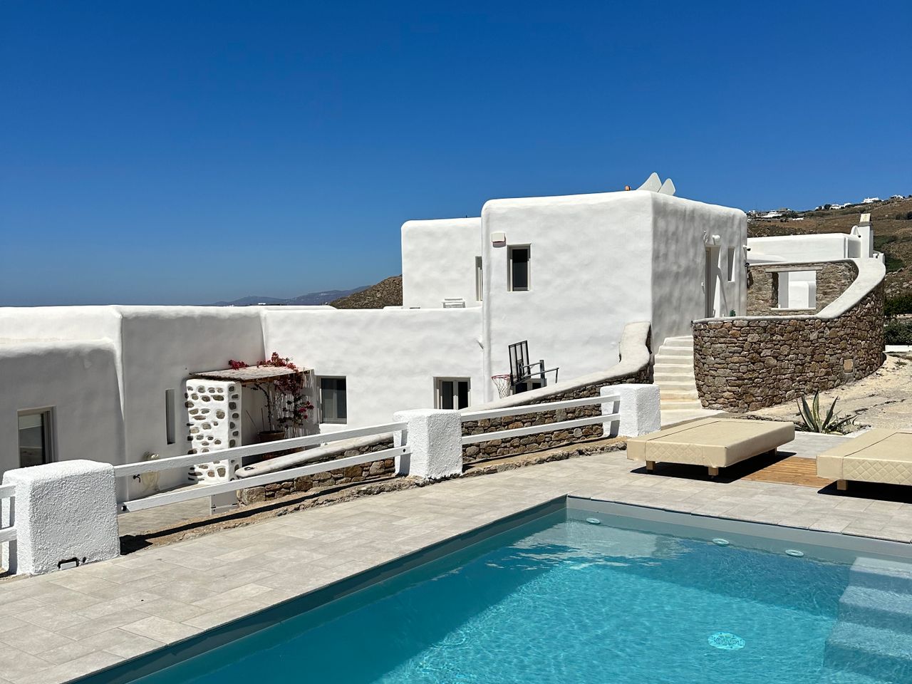 Piscine et terrasse d'une villa méditerranéenne blanche sous un ciel bleu