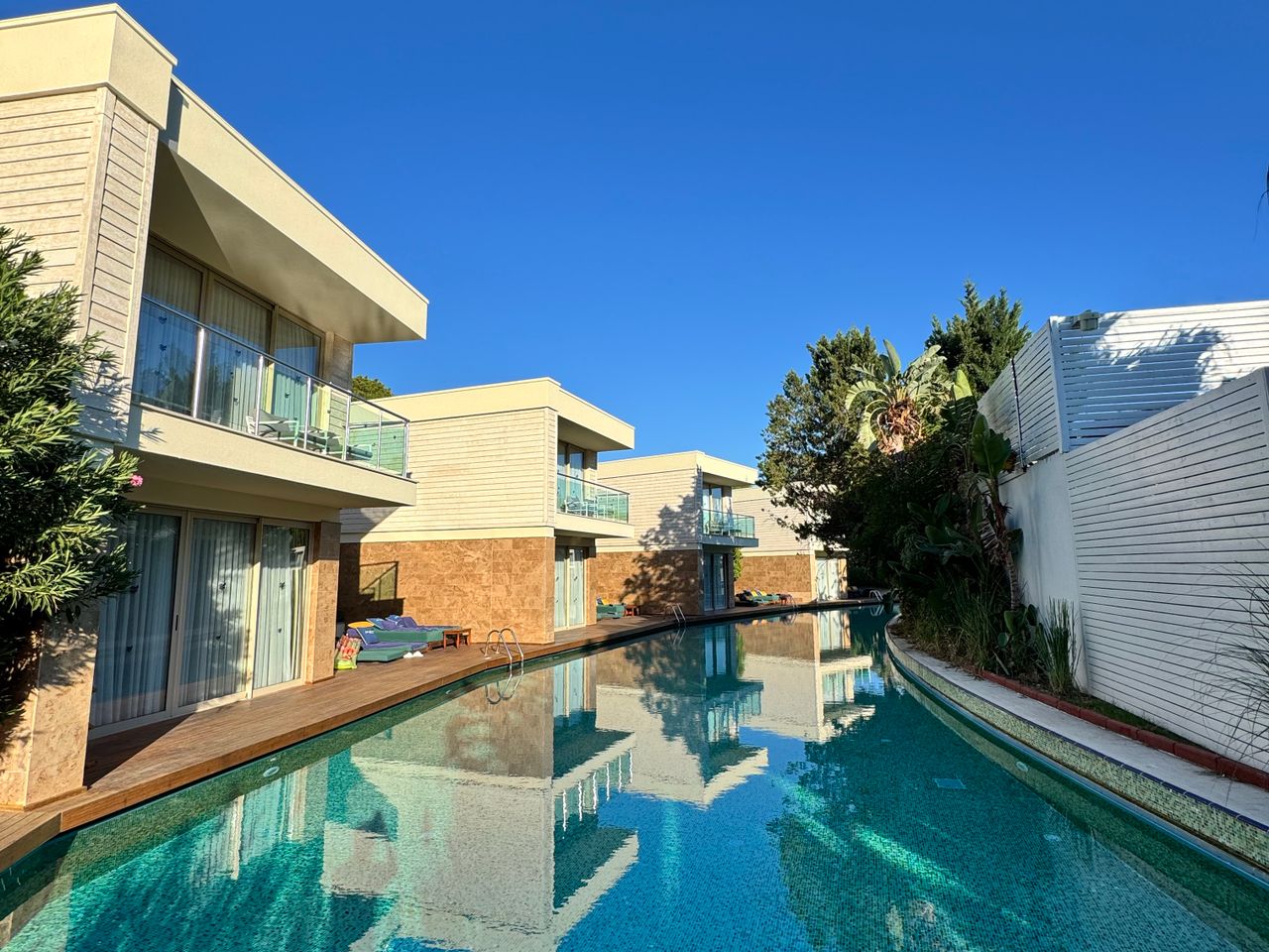 Longue piscine miroir bordée de villas contemporaines
