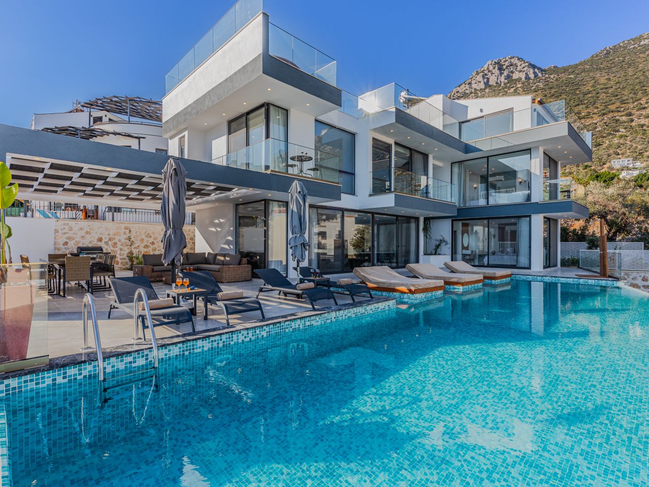 Grande piscine à débordement en mosaïque devant une villa contemporaine